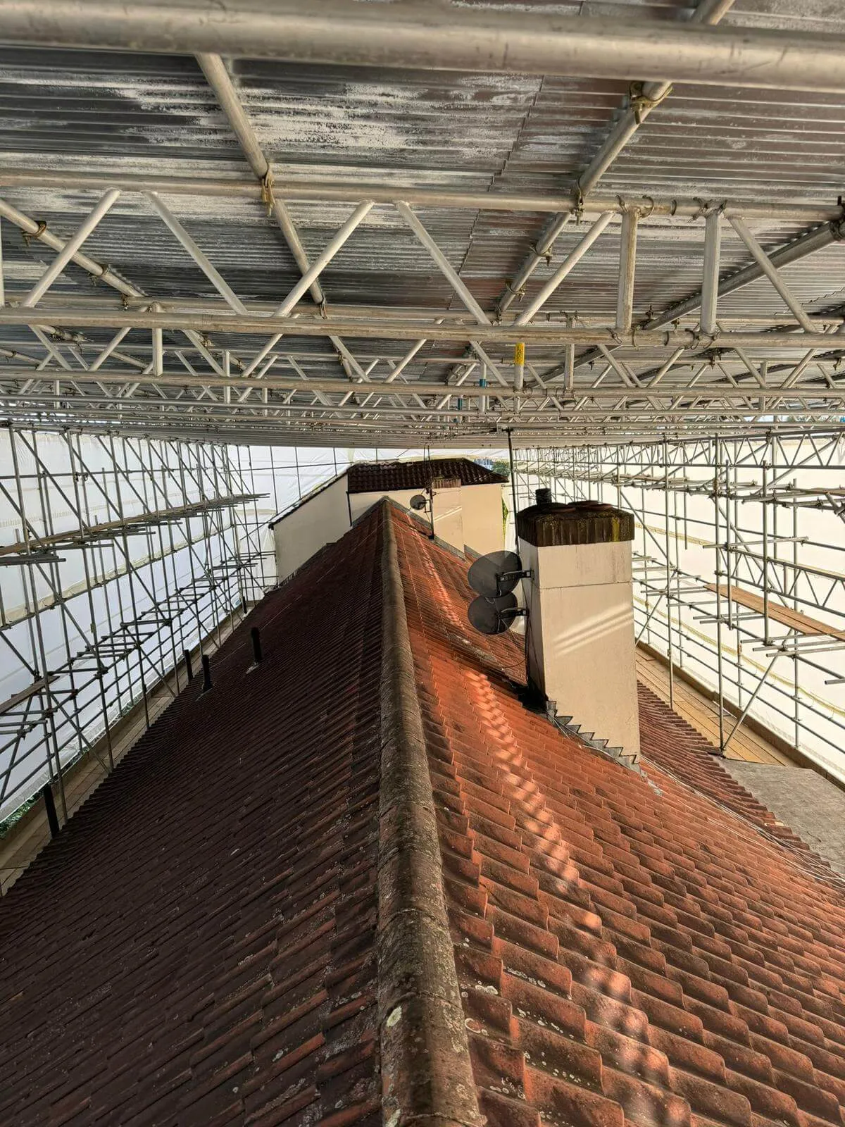 Temporary roof scaffolding with fully sheeted encapsulation keeping a building watertight during roof works
