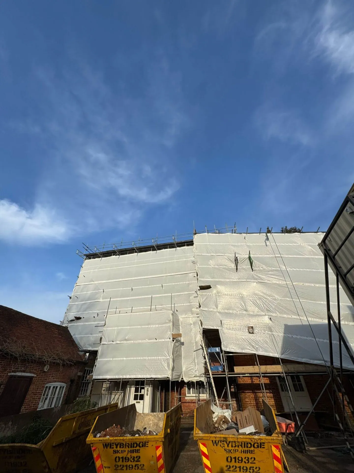 Fully sheeted temporary roof scaffolding protecting a building during a roof strip
