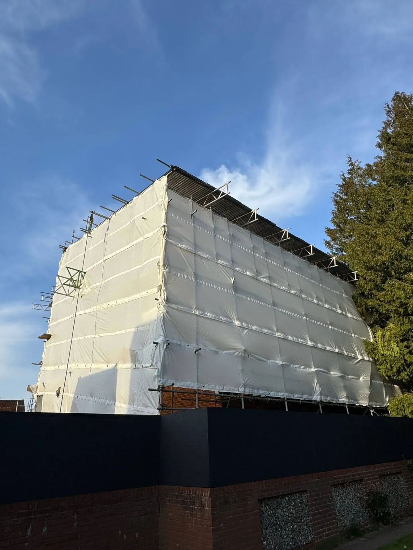 Temporary roof scaffolding with fully sheeted encapsulation keeping a building watertight during roof works