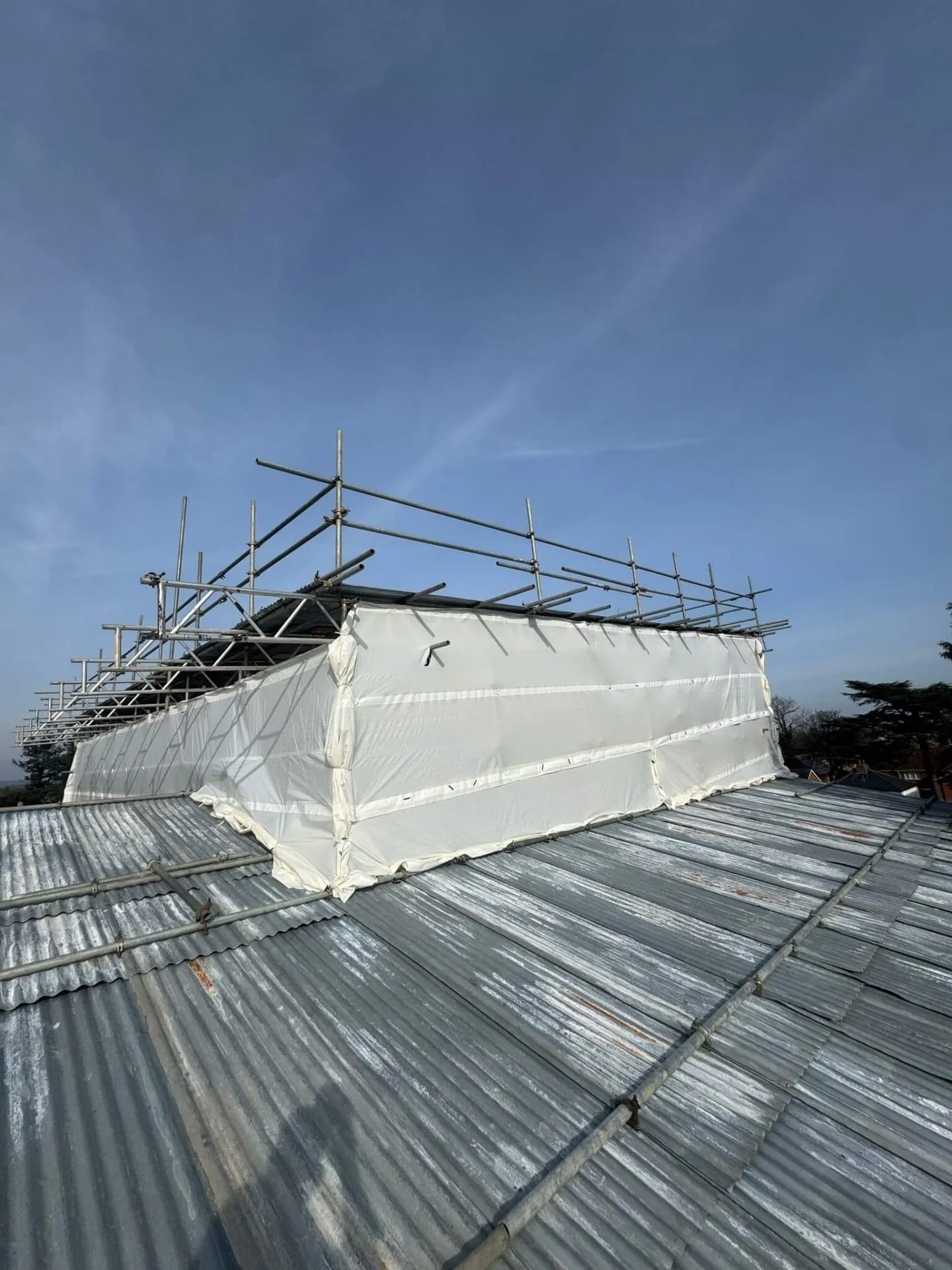 Temporary roof scaffolding with fully sheeted encapsulation keeping a building watertight during roof works
