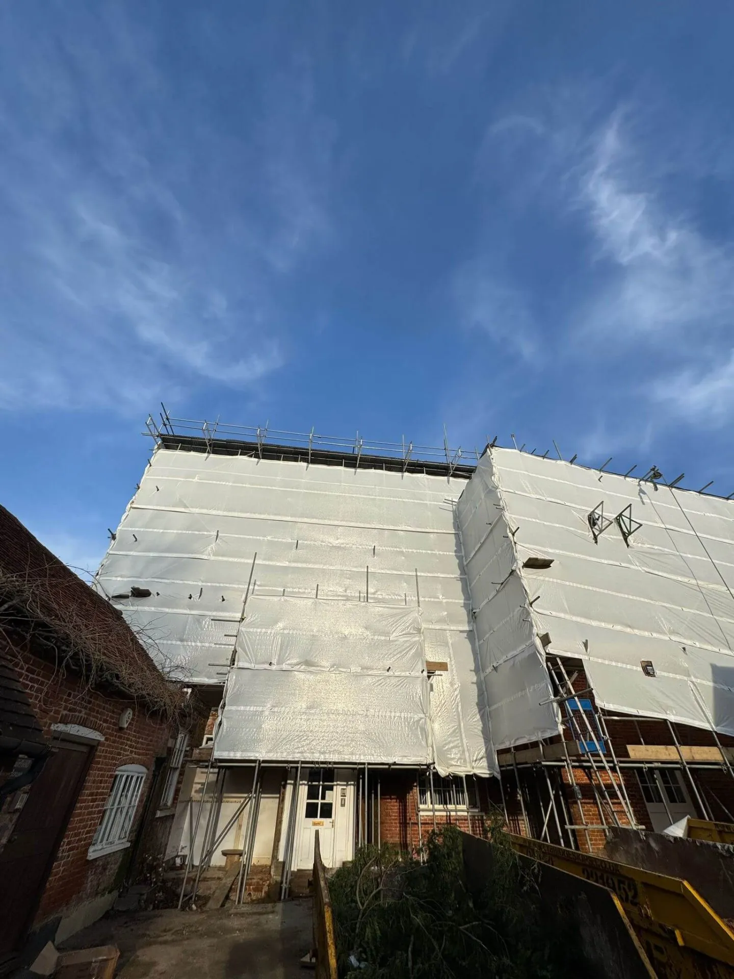 Temporary roof scaffolding with fully sheeted encapsulation keeping a building watertight during roof works