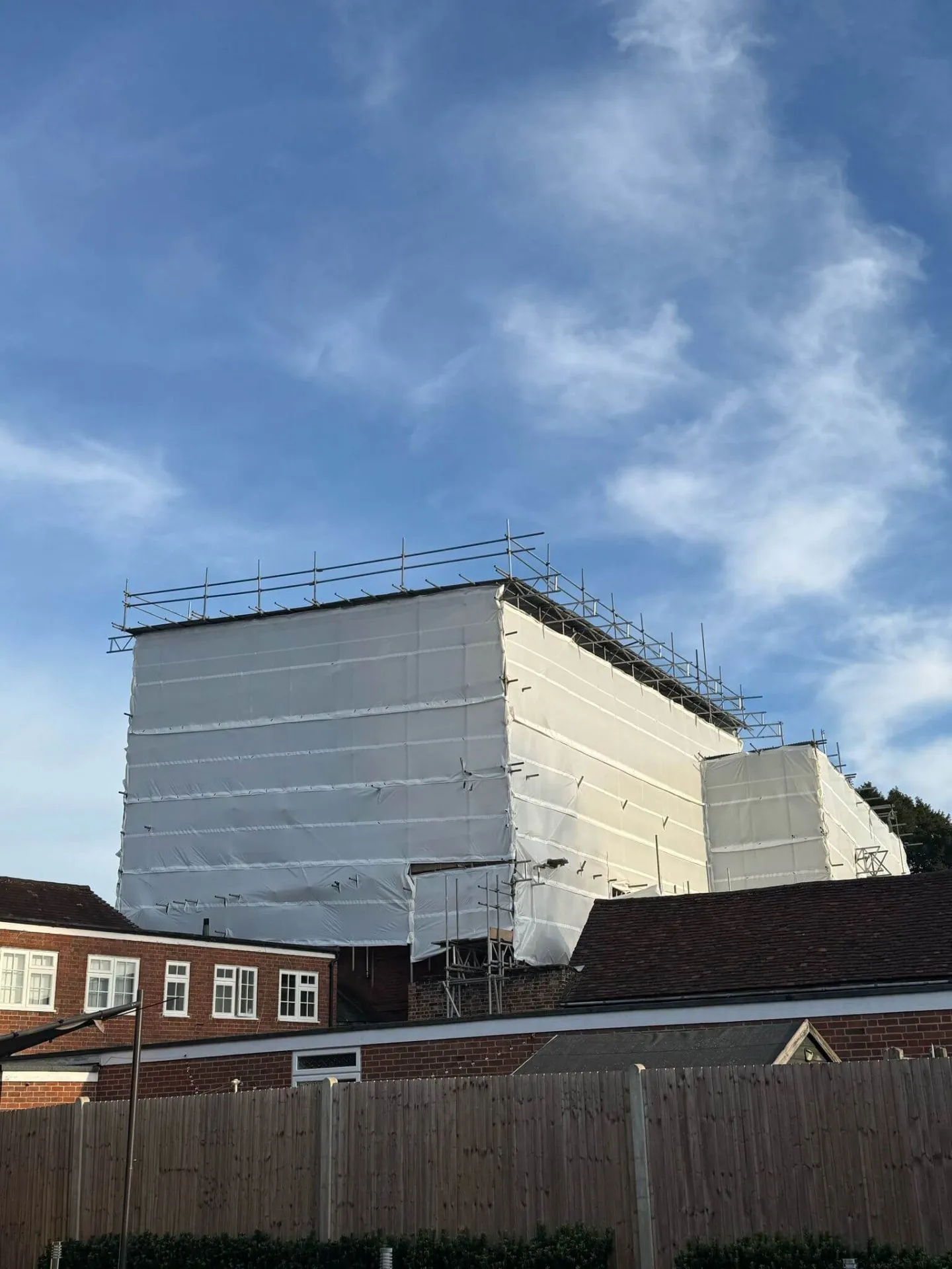 Temporary roof scaffolding with fully sheeted encapsulation keeping a building watertight during roof works